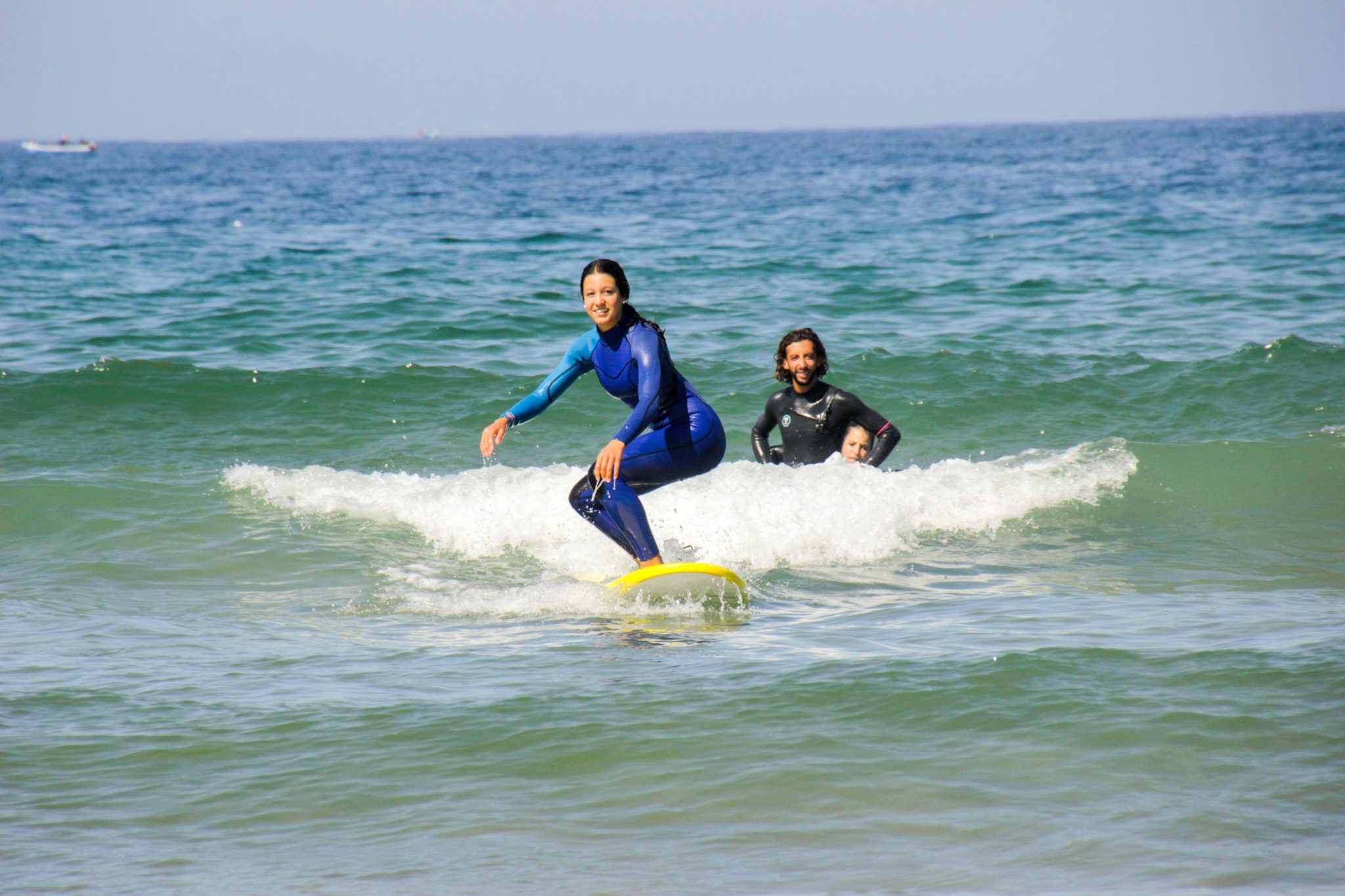 Two beginners riding their first waves on soft-top boards