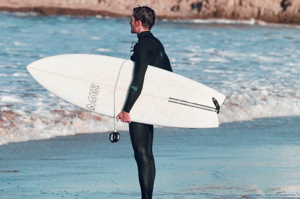 Surfer with board under his arm reading the break before paddling out